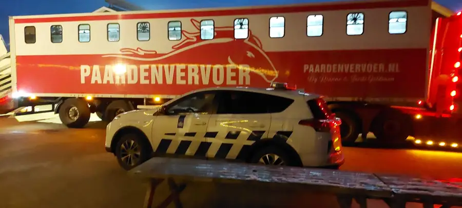 Een vrachtwagen voor paardenvervoer staat 's avonds geparkeerd naast een overheidswagen. De foto is gemaakt tijdens de inzet waarbij de paarden na het schietincident veilig werden weggehaald en naar een opvanglocatie zijn vervoerd.